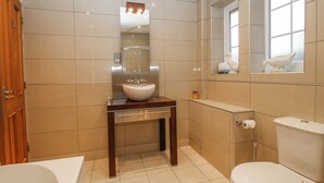 Un baño con lavamanos, espejo, inodoro y bañera.