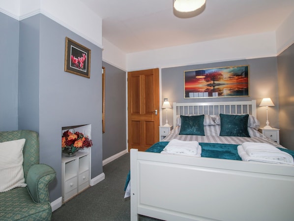 A bedroom with a bed, two bedside tables, a nightstand, a chair, and a wall-mounted painting. - The Rumbles (Ludlow)