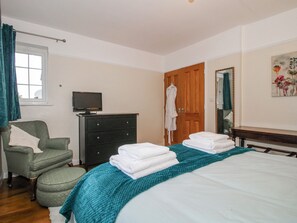 A bedroom with a bed, a chair, a dresser, a television, and a door. - The Rumbles (Ludlow)