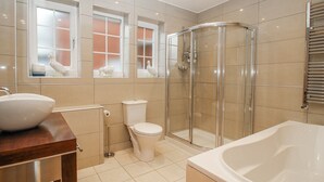 Un baño moderno con ducha de mampara de vidrio, bañera blanca y retrete.
