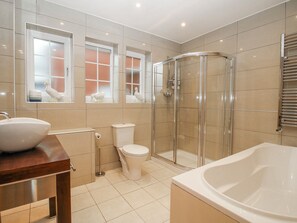 A modern bathroom with a glass-enclosed shower, a white bathtub, and a toilet. - The Rumbles (Ludlow)