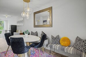 A dining area with a round table, black velvet chairs, a patterned sofa, and a large mirror. - Vail Simba Run • Pool, Hot Tub, & Shuttle (Vail)
