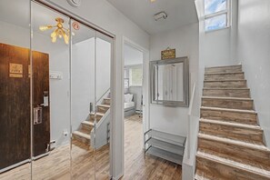 Ein modernes Interieur mit einer Holztreppe, einer Glastür und einem Bett im Hintergrund.