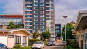 A multi-story residential building with a central courtyard, a parking area, and a street view. - River view Downtown apartment 12th floor (Valdivia)