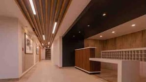A modern reception area with a long corridor, wooden panel ceiling, and a reception desk. - River view Downtown apartment 12th floor (Valdivia)