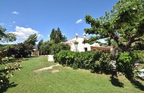 Ein Haus mit einem gepflegten Rasen, einem großen Baum und blauem Himmel.