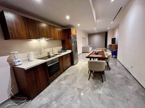 Une cuisine moderne avec des meubles en bois, un four encastré et un coin repas comprenant une table et des chaises.