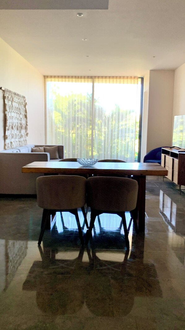 Un coin repas avec une table et des chaises, un canapé et un téléviseur en arrière-plan.