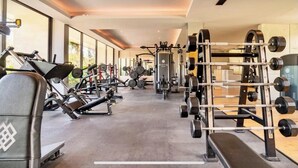 Une salle de sport équipée de divers appareils d’entraînement, notamment des tapis de course, des appareils de musculation et des poids libres.
