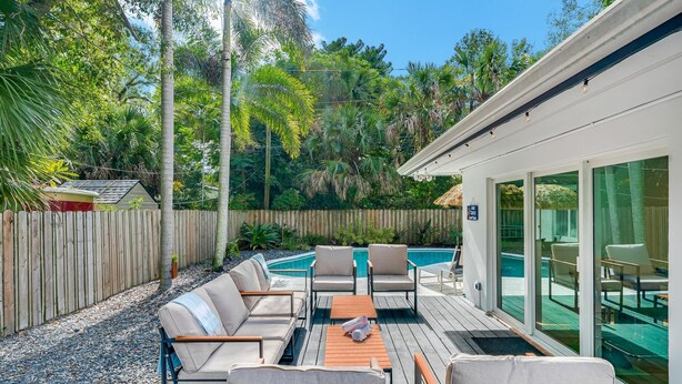 Une terrasse avec des sièges extérieurs, une piscine et une clôture en bois.