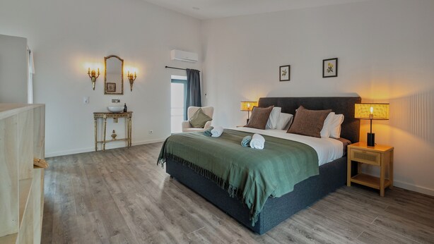 A bedroom with a bed, bedside table, lamp, and wall-mounted mirror. - Luxury house in historic center Tomar with large and sunny private courtyard (Tomar)