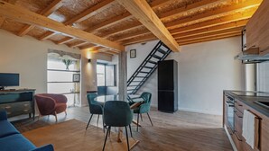 A modern kitchen with wooden beams, a dining area with chairs, and a staircase leading to another level. - Luxury house in historic center Tomar with large and sunny private courtyard (Tomar)