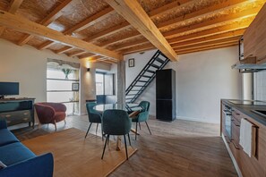 Eine moderne Küche mit Holzbalken, einem Essbereich mit Stühlen und einer Treppe zu einer weiteren Ebene.