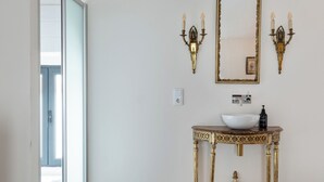 A bathroom with a large window, a white sink, a gold-framed mirror, and wall-mounted sconces. - Luxury house in historic center Tomar with large and sunny private courtyard (Tomar)