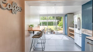 A modern kitchen with a dining area, a coffee sign, and a view of the outdoors. - The Reef in Fort Lauderdale (Fort Lauderdale)