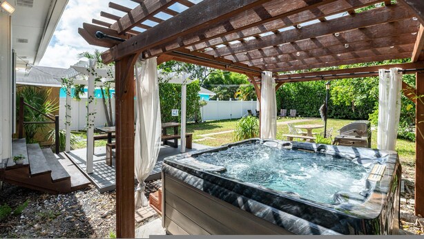 A hot tub under a wooden pergola in a backyard with a patio and outdoor furniture. - The Reef in Fort Lauderdale (Fort Lauderdale)