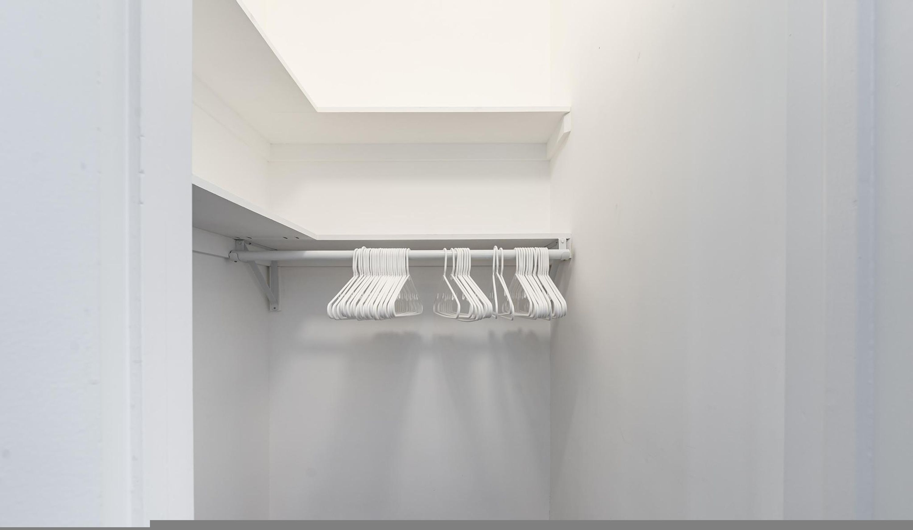 Un bagno bianco con un lucernario, un portasciugamani con diversi asciugamani e una parete bianca.