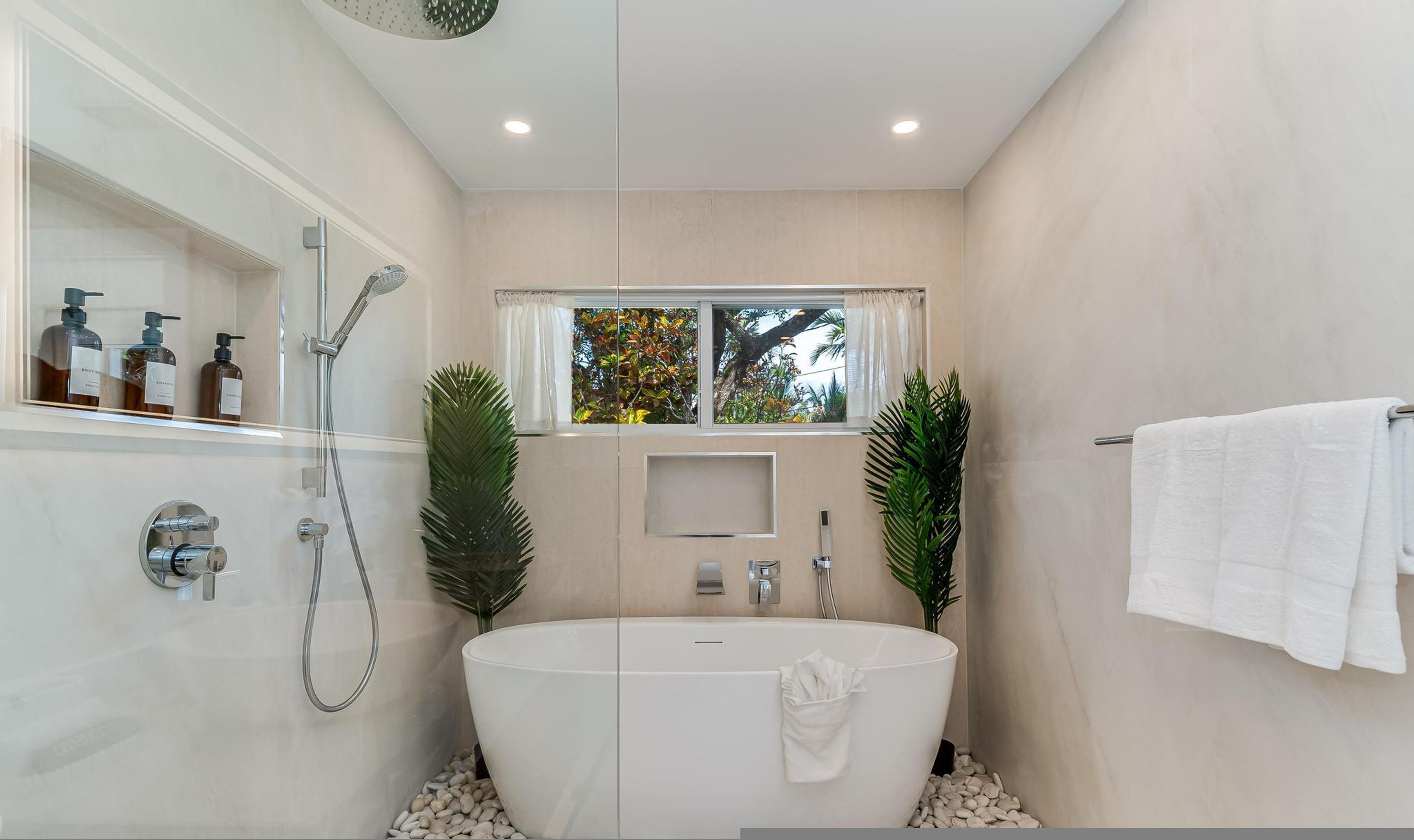 Une salle de bain moderne avec une baignoire sur pieds, une douche et une fenêtre donnant sur la verdure.