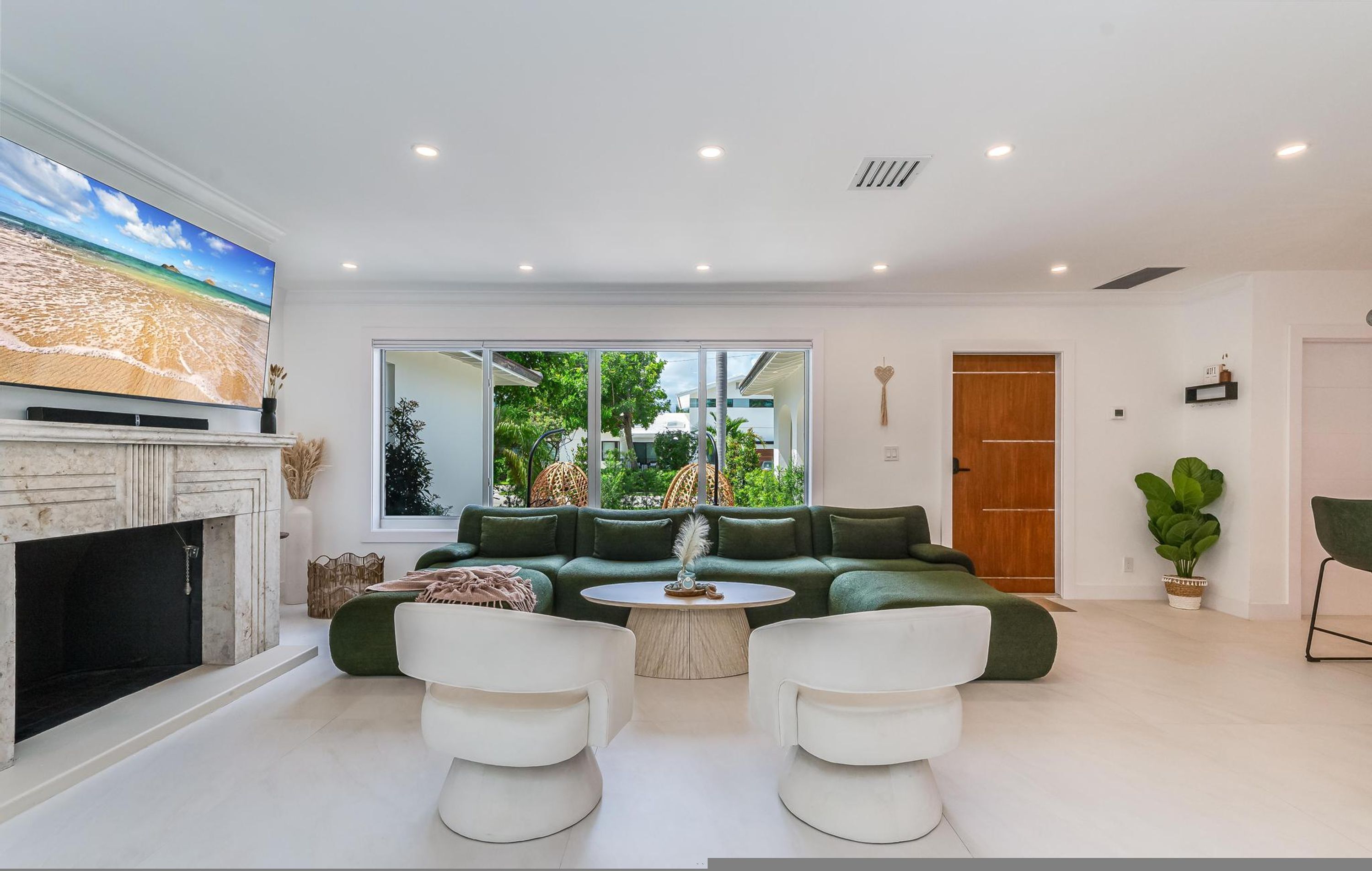 A modern living room with a fireplace, a large flat-screen TV, a green sofa, and a coffee table.