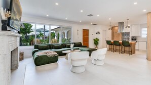 A modern living room with a green sofa, white chairs, and a fireplace. - Fox Pearl 4Bd Pool House- Las Olas Luxury Getaway (Fort Lauderdale)
