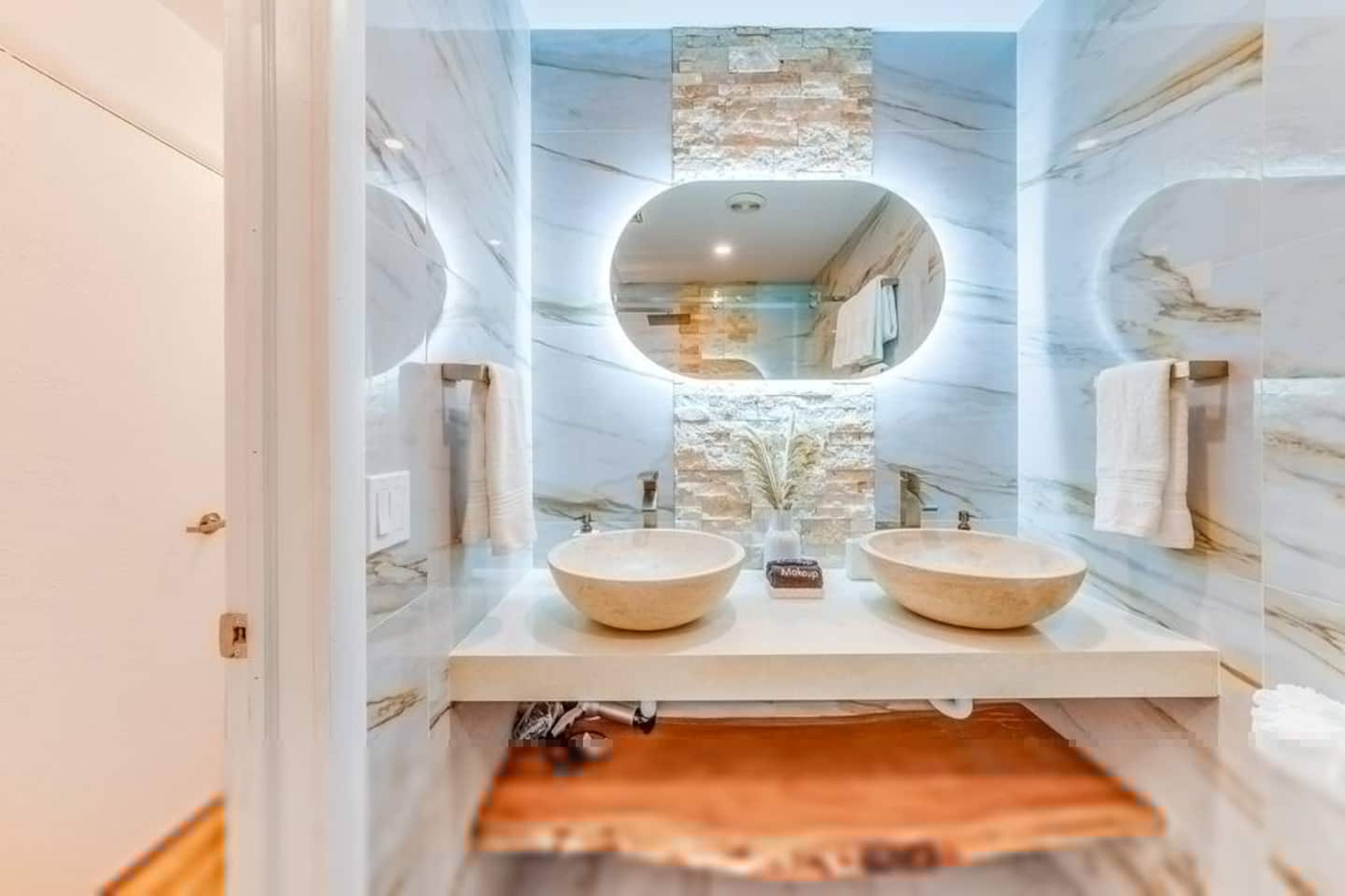 Un baño con dos lavamanos, un espejo y una pared decorativa de piedra.