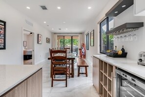 Eine moderne Küche mit Essbereich, Einbauofen und Weinkühlschrank.
