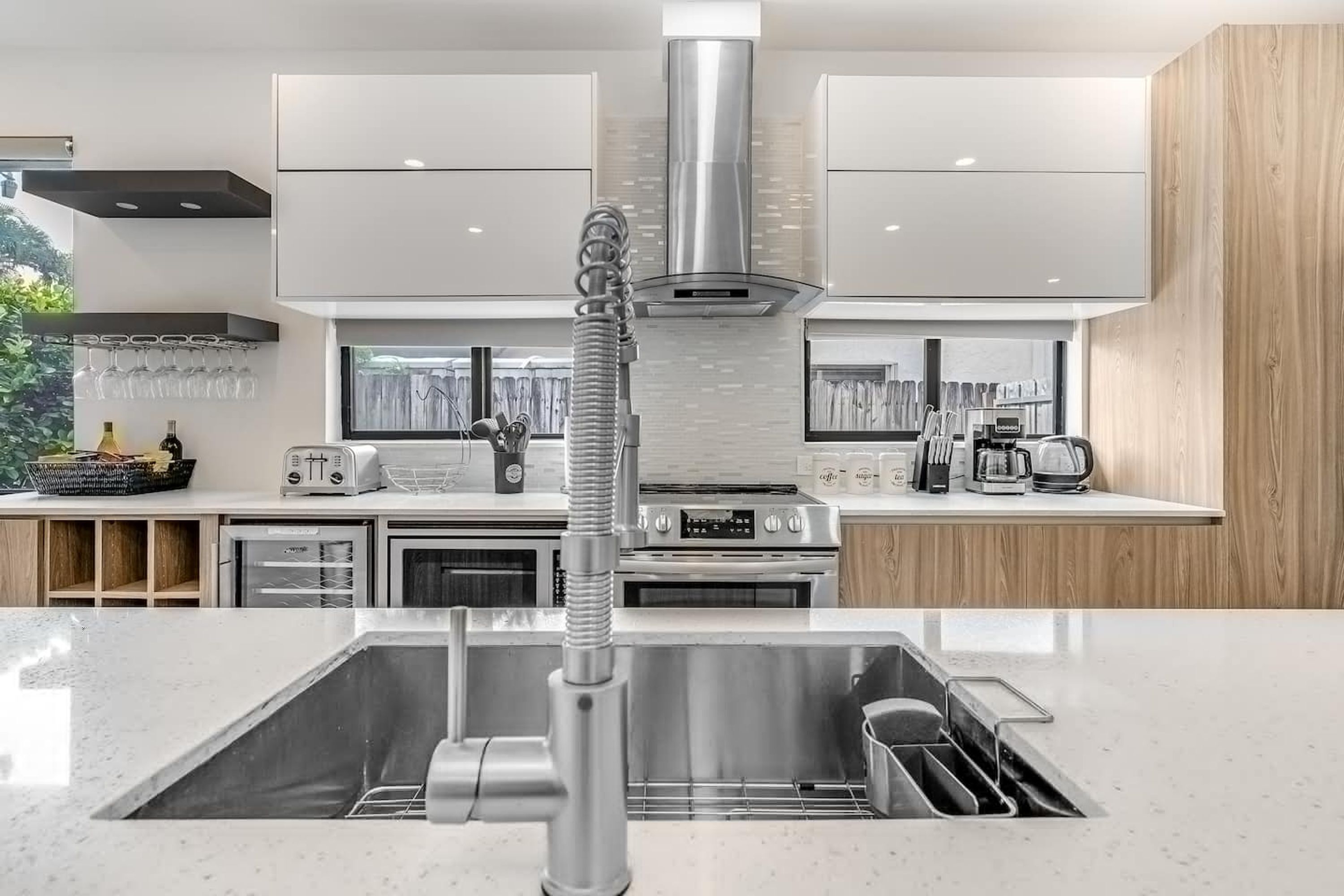 A modern kitchen with stainless steel appliances, a central island with a sink, and a view of the outdoors.