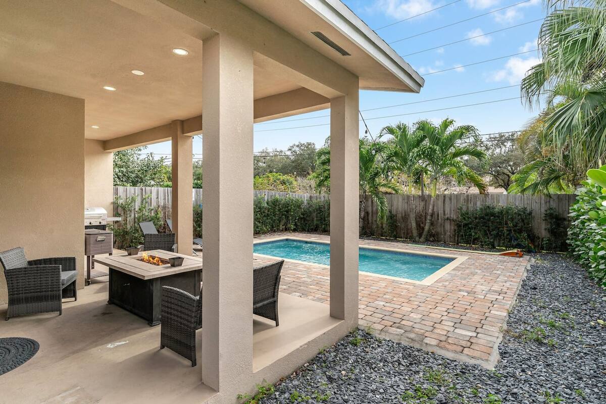 A covered patio with a pool, outdoor furniture, and a grill.
