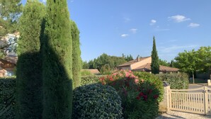 A residential garden with a gravel path, neatly trimmed hedges, and a variety of flowering plants. - Ardèche Villa for Rent (Vallon-Pont-d'Arc)