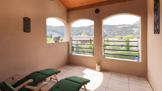 A room with three green reclining chairs, a tiled floor, and a view of a mountainous landscape through arched windows. - Ardèche Villa for Rent (Vallon-Pont-d'Arc)
