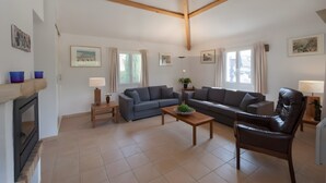 A living room with a fireplace, two sofas, a coffee table, and a leather armchair. - Ardèche Villa for Rent (Vallon-Pont-d'Arc)