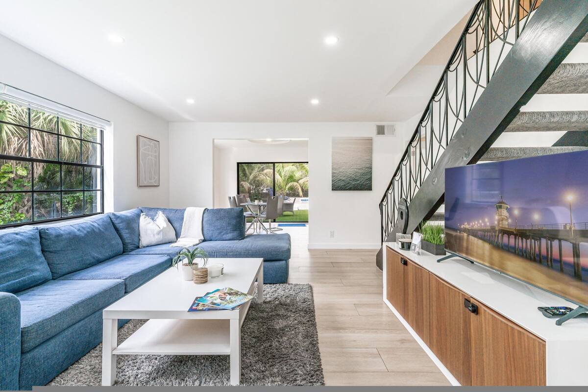 A modern living room with a blue sofa, white coffee table, and a TV on a wooden cabinet.