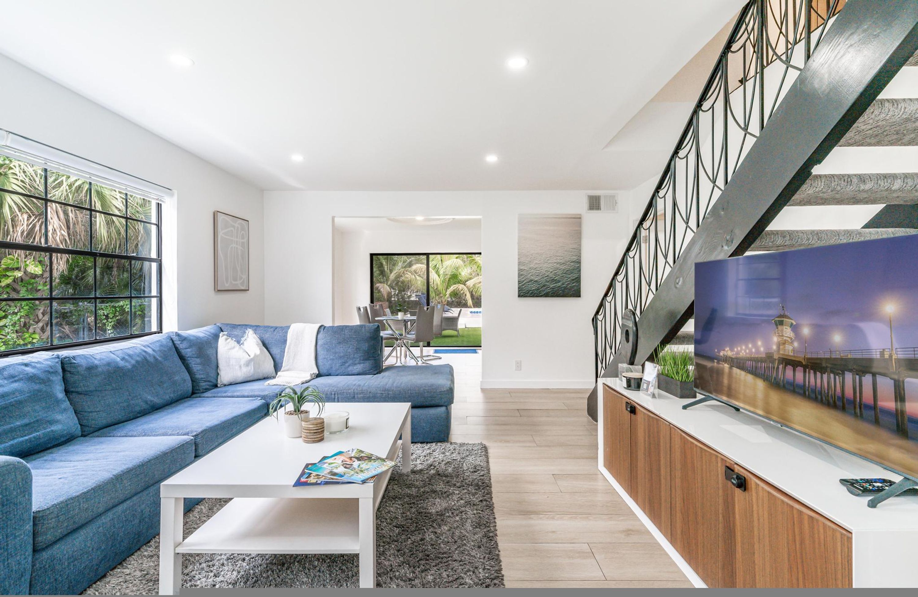 A modern living room with a blue sofa, white coffee table, and a TV on a wooden cabinet.