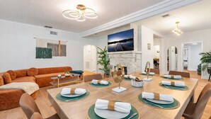 A modern dining room with a wooden table set for six, a fireplace, and a large TV mounted on the wall. - Fox Of Oz- Pool Spa Oasis Villa (Fort Lauderdale)