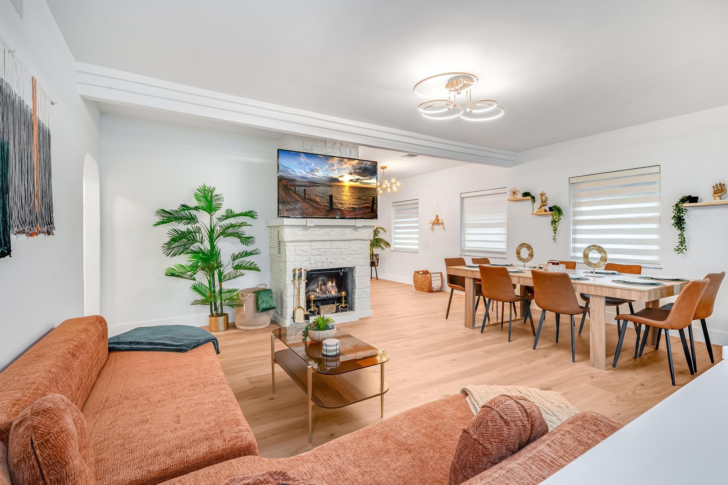 Un salon moderne avec une cheminée, un coin repas et un téléviseur fixé au mur.