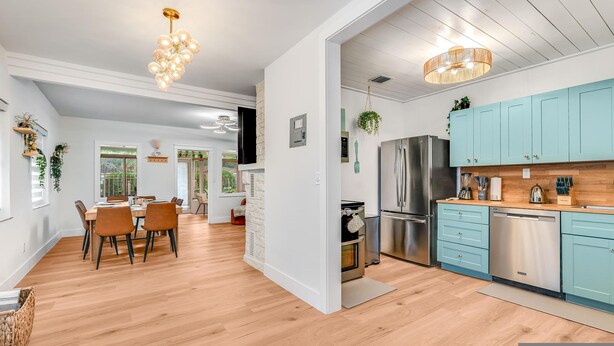 A modern kitchen with light blue cabinets, stainless steel appliances, and a wooden floor. - Fox Of Oz- Pool Spa Oasis Villa (Fort Lauderdale)