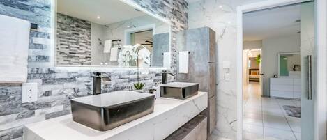 A modern bathroom with a large mirror, two sinks, and a marble countertop.
