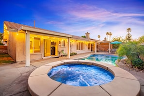 Una propiedad residencial con piscina, mobiliario exterior y una entrada bien iluminada.