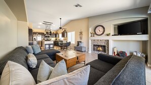 A living room with a sofa, coffee table, fireplace, and a television mounted on the wall. - Private Pool & Spa | Walk to Tennis Garden (La Quinta)