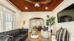 Ein Wohnzimmer mit einer schwarzen Ledersofa, einem weißen Sessel, einem Holztisch und einem Deckenventilator.