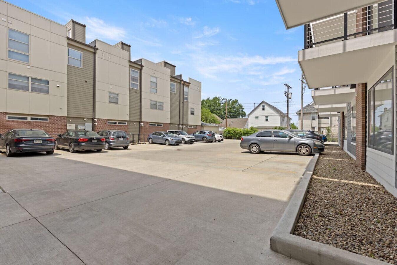 A parking lot with several cars, a building with a brick facade, and a clear sky.