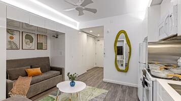 A modern living room with a grey sofa, a small round table, and a ceiling fan.