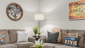 Ein Wohnzimmer mit einer Couch, einem Couchtisch, einer Lampe, einer Uhr und einem Willkommensschild.