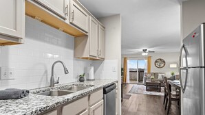 Eine moderne Küche mit weißen Schränken, Granit Arbeitsplatten, Edelstahlgeräten und einem Essbereich mit Holzböden.