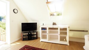 Habitación con televisión, mueble blanco, suelo de madera y ventana.