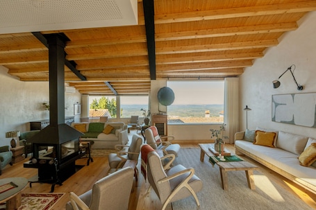 A spacious living room with a fireplace, comfortable seating, and large windows offering a view.. Marvão Hotel Museu