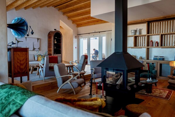 Una sala de estar acogedora con chimenea, muebles de madera y vistas a través de un ventanal.