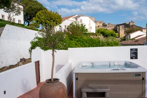 A spa area with a hot tub, a large vase, and a view of a historic building. - Marvão Hotel Museu (Marvão)