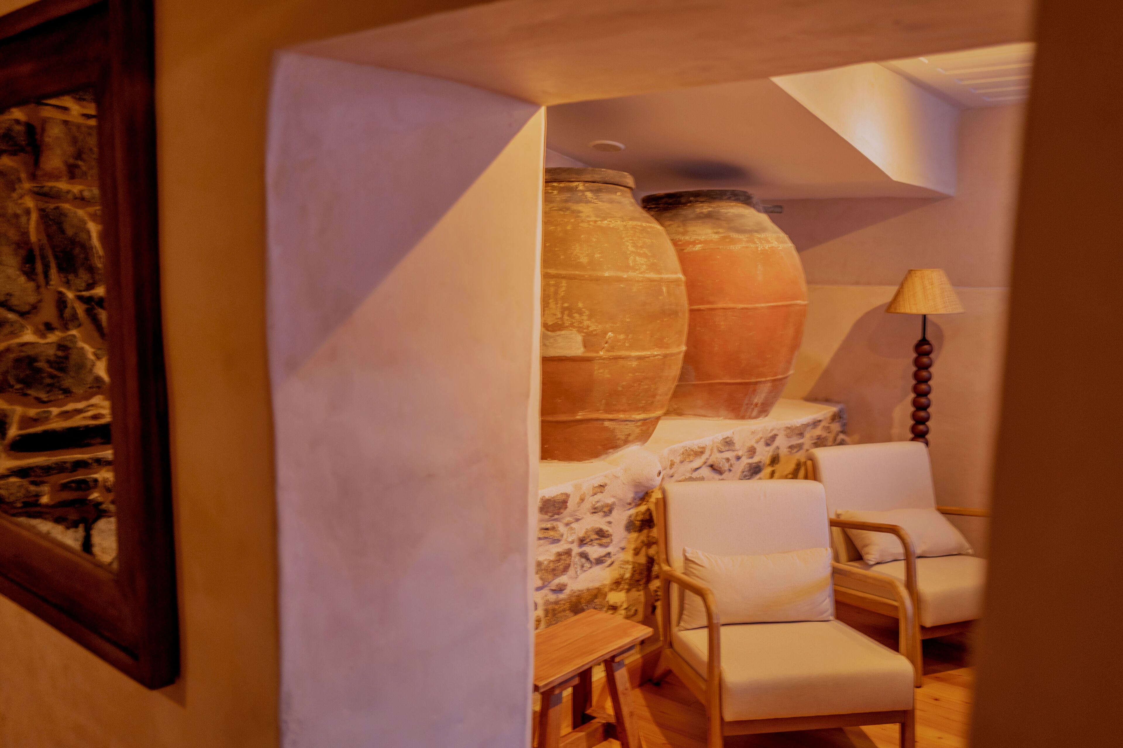A cozy room with stone walls, a wooden floor, and two white chairs.