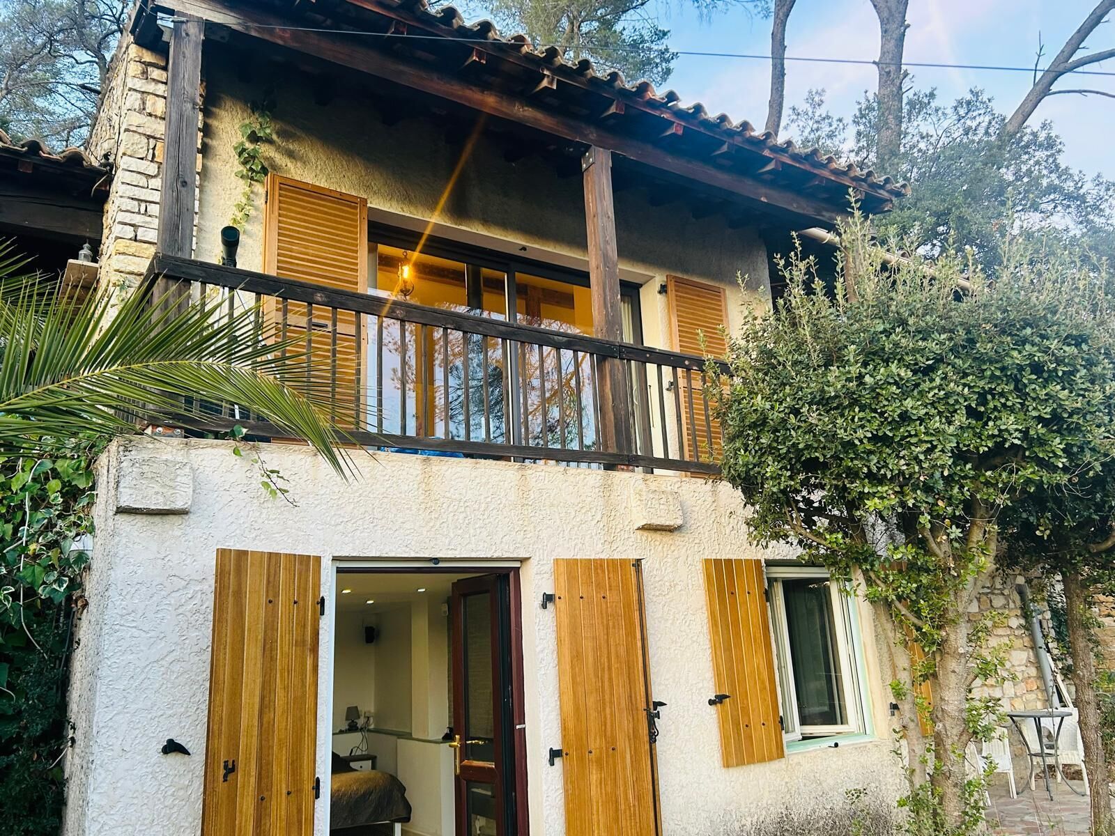 A two-story building with a balcony, wooden shutters, and a stone facade.
